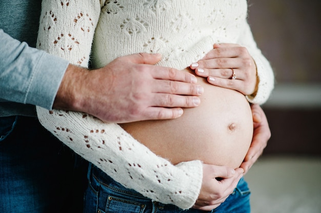 Beschnittenes Bild des Ehemanns, der Bauch seiner schwangeren Frau hält