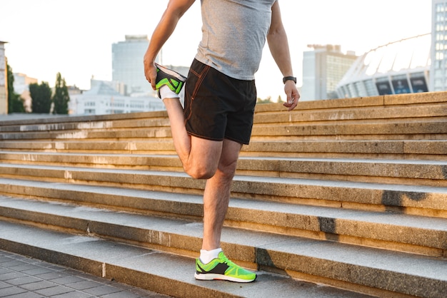 Beschnittenes Bild eines jungen Sportlers, der Beine streckt