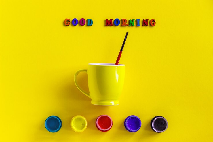 Beschriftung Guten Morgen, Gläser Gouache und gelbe Tasse mit Pinsel. Konzept