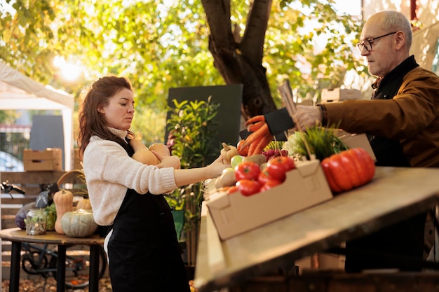 Besitzer frischer Bauernhöfe beginnen den Tag mit Bio-Naturprodukten und arbeiten am Marktstand, um gesunde Produkte zu verkaufen. Junge Frau bringt Obst und Gemüse auf den Bauernmarkt.