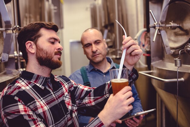Foto besitzer untersucht bier im glas