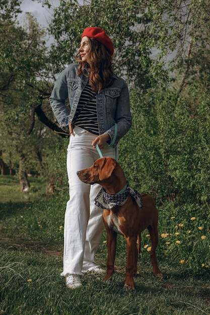 Besitzerin in trendiger Baskenmütze und Jeansjacke mit Rhodesian Ridgeback Hund