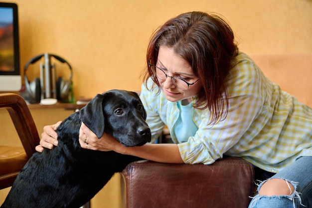 Besitzerin von mittlerem Alter zusammen mit jungem Hund zu Hause