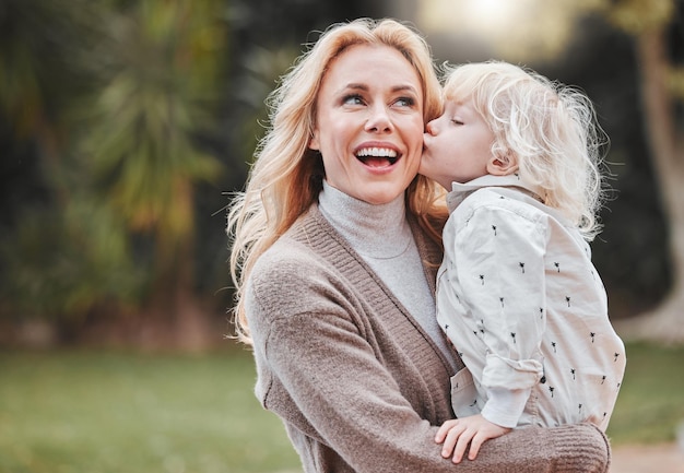 Un beso para la mejor mamá Foto de una mujer y su adorable hijo pasando tiempo al aire libre