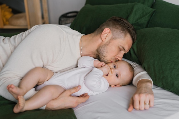 El beso de papá de su hijo de seis meses acostado en la cama en casa