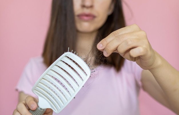 besockte frau schleppen gefallene haare vom pinsel rosa hintergrund isolierte mädchenhaare fallen heraus problem