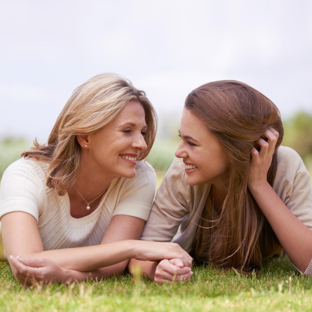 Besondere Zeit mit ihrer Tochter Eine liebevolle Mutter und Tochter, die Seite an Seite im Gras liegen