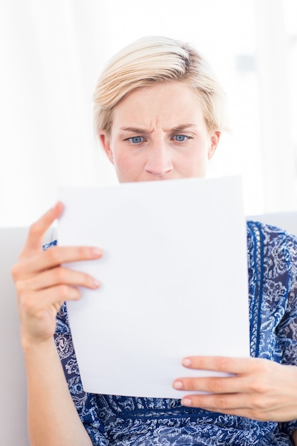 Foto besorgte blondine, die ein papier lesen