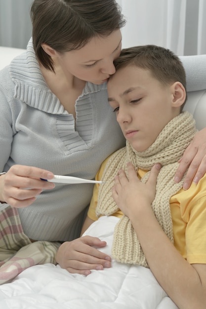 Besorgte junge Mutter und kranker Sohn im Bett