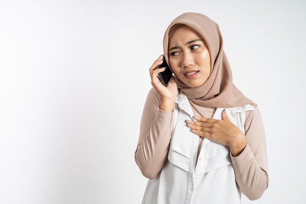 Besorgte muslimische Frau im Hijab, die mit einem Handy telefoniert