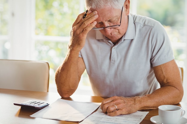 Besorgter älterer Mann mit Steuerdokumenten zu Hause