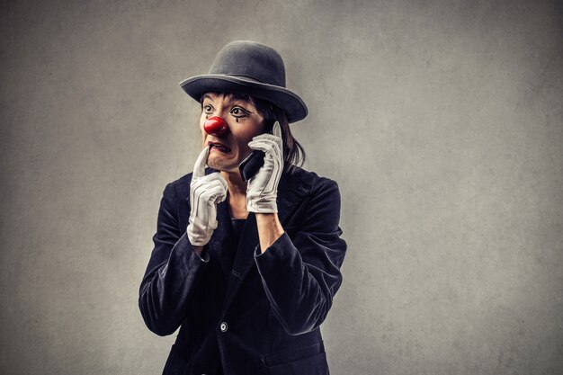 Besorgter Clown, der am Telefon spricht