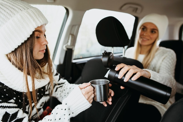 Beste Freunde, die im Auto Kaffee trinken