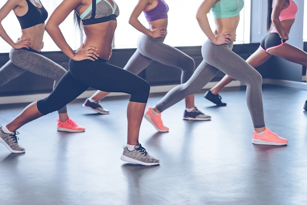 Foto beste übung für ihre beute. seitenansicht eines teils junger frauen mit perfektem gesäß in sportbekleidung, die beim stehen vor dem fenster im fitnessstudio trainieren