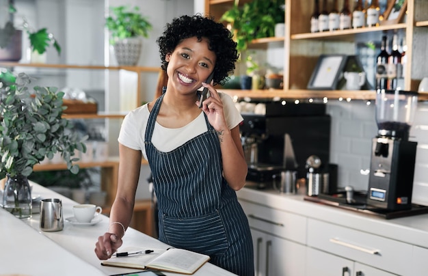 Bestellen von mehr Lagerbeständen bei ihren vertrauenswürdigen Lieferanten Porträt einer jungen Frau, die während der Arbeit in einem Café mit einem Mobiltelefon spricht