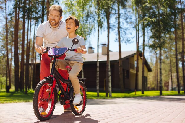 Bester Lehrer. Alarmliebender Vater lächelt und bringt seinem Sohn das Fahrradfahren bei