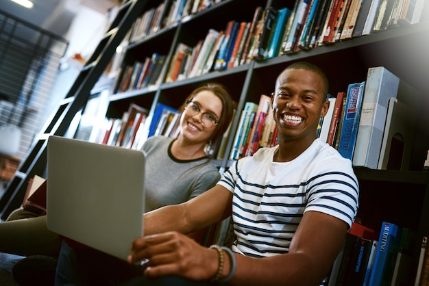 Bester Studienfreund aller Zeiten Porträt eines jungen Mannes und einer jungen Frau, die gemeinsam einen Laptop in einer College-Bibliothek verwenden