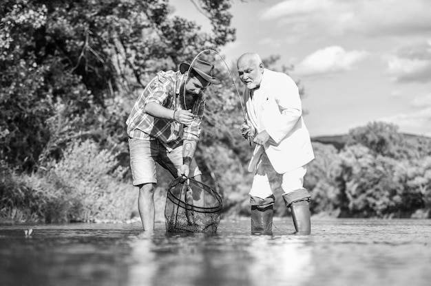 Bester Tag aller Zeiten Vater im Ruhestand und reifer bärtiger Sohn Fang- und Fischereikonzept Fliegenfisch-Hobby des Geschäftsmanns Ruhestand Fischerei glückliche Fischer Freundschaft Zwei männliche Freunde, die zusammen fischen