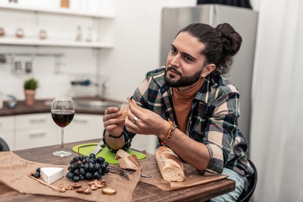 Bestes Essen. Positiver netter Mann, der ein tolles Abendessen hat, während er seine Ruhe zu Hause genießt?