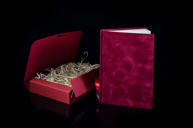 Bestes Geschenk für Männer Mann Geschenkkonzept Rotes Notizbuch mit roter Geschenkkiste auf schwarzem Hintergrund Kopieren Sie den Text mit Leerzeichen Valentinstag Hochzeit Geburtstag und besondere Anlässe Geschenk Konzept Kopieren Sie die Leerzeichen für den Text