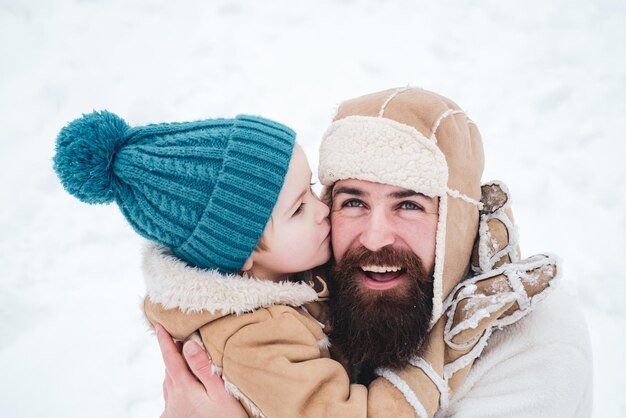 Bestes Winterspiel für eine glückliche Familie Der glückliche Familiensohn umarmt seinen Vater im Winterurlaub Papa und Junge lächeln