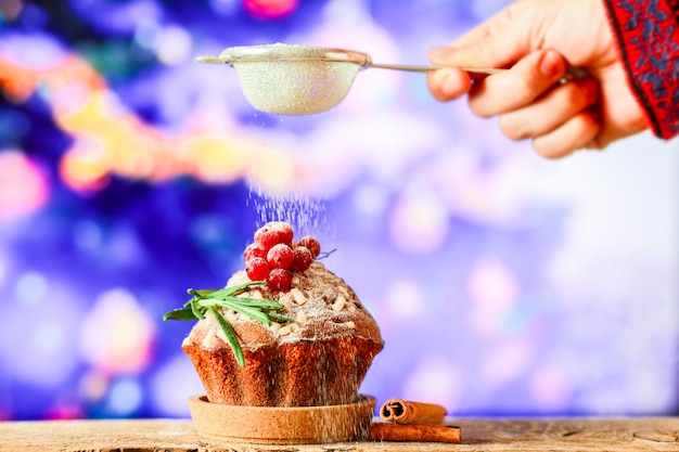 Bestreuen Sie den Weihnachtscupcake mit Puderzucker Süße für Weihnachten auf dem Hintergrund von
