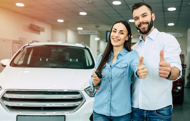 Besuchen Sie das Autohaus Glückliches junges Paar wählt und kauft ein neues Auto für die Familie