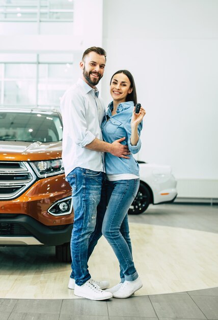 Besuchen Sie das Autohaus Glückliches junges Paar wählt und kauft ein neues Auto für die Familie