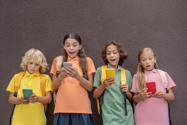 Beteiligt. Vier Kinder spielen Online-Spiele auf ihren Smartphones und sehen involviert aus