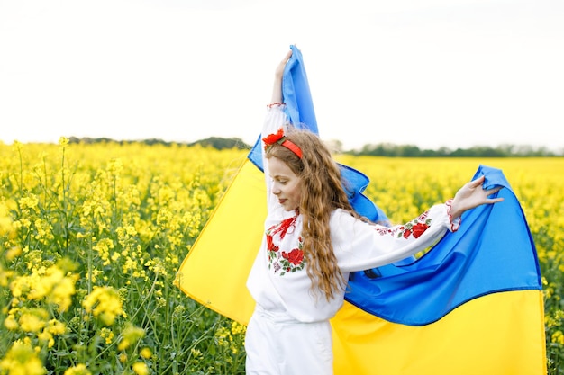 Beten Sie für die Ukraine Kind mit ukrainischer Flagge im Rapsfeld Mädchen mit Nationalflagge, die für den Frieden betet Glückliches Kind, das den Unabhängigkeitstag feiert