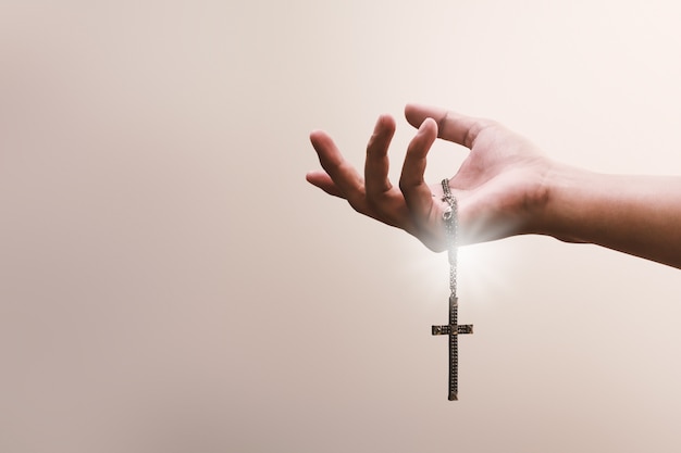 Foto betende hände halten ein kruzifix oder ein kreuz aus metall mit dem glauben an die religion und den glauben an gott