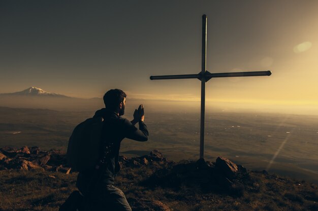 Betender Mann und Kreuz im Berg