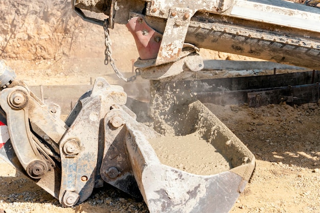 Betonmischwagen, der auf einer Baustelle frischen, nassen Beton in Baggereimer gießt