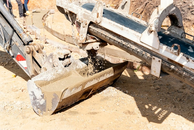 Betonmischwagen, der auf einer Baustelle frischen, nassen Beton in Baggereimer gießt