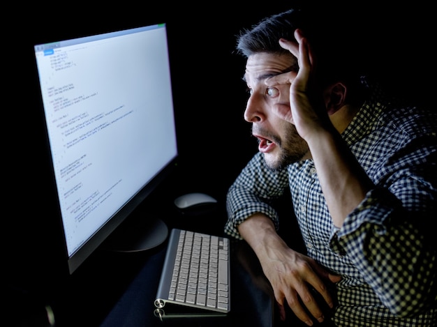 Betonter Softwareentwickler mit Büro des Computers zu Hause