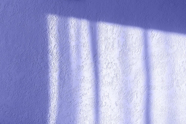 Betonwand in der Farbe Veri Peri 2022 gestrichen. Es gibt Licht aus dem Fenster darauf
