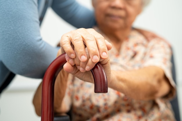 Betreuerin hilft asiatischer älterer Frau mit liebevoller Betreuung, Ermutigung und Empathie