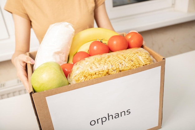 Betreuung der Waisenkinder Ein freiwilliges Mädchen hält eine Kiste mit Lebensmitteln