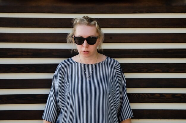 Betrunkene Frau in angespannter Pose mit Sonnenbrille, strenger Blick. Müde empörte Frau bereit zum Konflikt