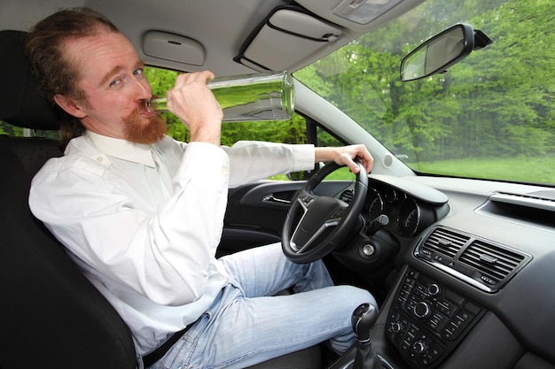 Betrunkener Mann im Auto mit einer Flasche Alkohol