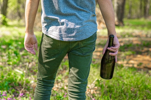 betrunkener Mann mit einer Flasche Alkohol in der Hand in der Natur