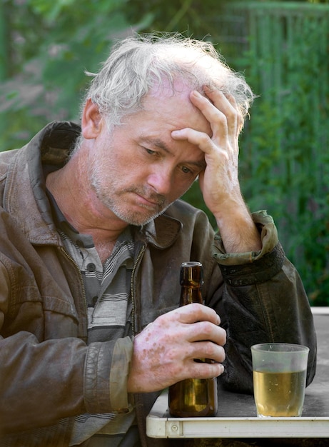 Foto betrunkener mann mit flasche bier und glas auf natürlichem hintergrund