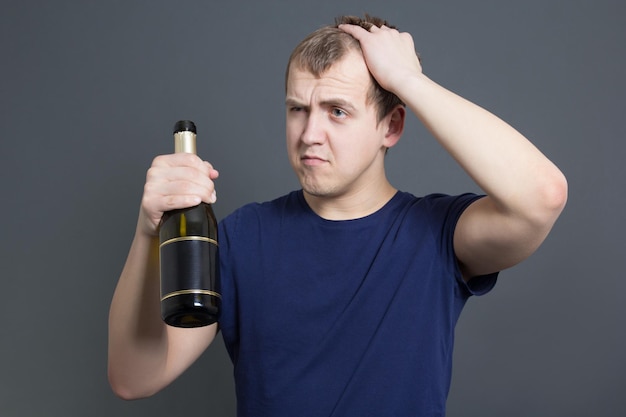 betrunkener mann mit flasche champagner über grau