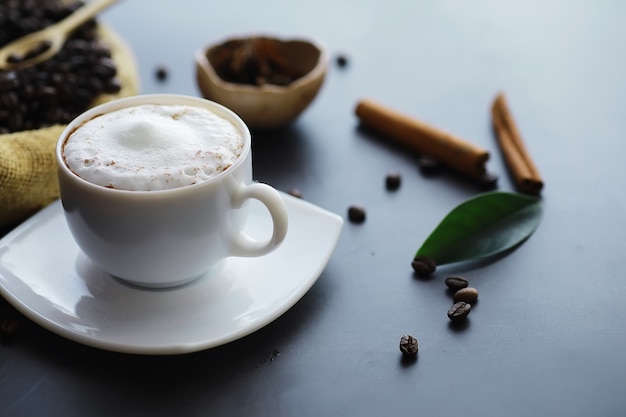 Beutel Kaffee. Auf dem Tisch geröstete Kaffeebohnen. Kaffeebohnen mit grünen Blättern zum Kochen.