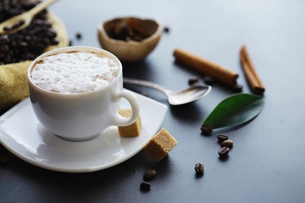 Beutel Kaffee. Auf dem Tisch geröstete Kaffeebohnen. Kaffeebohnen mit grünen Blättern zum Kochen.