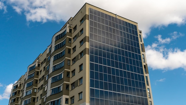 Bewegung der Wolken vor dem Hintergrund eines modernen energieeffizienten Gebäudes Mehrstöckiges Wohnhaus mit Sonnenkollektoren an der Wand Erneuerbare Energien in der Stadt