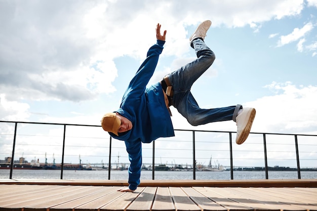 Bewegungsaufnahme eines jungen Mannes, der Breakdance-Stunts im Freien gegen den Kopierraum des Himmels macht