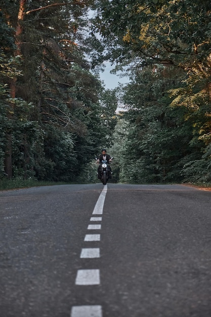 Bewegungsunschärfe Ein junger Biker mit Helm fährt schnell mit hoher Geschwindigkeit auf einem Waldweg in Bewegung