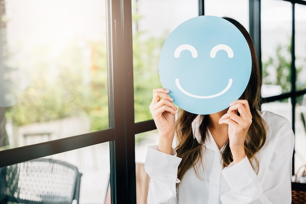 Bewertung der Kundenerfahrung. Weibliches Holding-Lächeln Emoji, glückliche Geschäftsfrau zeigen ausgezeichnete Bewertung mit Smiley-Gesichtssymbol auf blauem Kreispapier im Shop-Feedback-Zufriedenheit guter Service, Kompliment-Tag