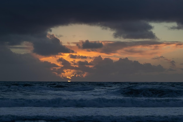 Bewölkter heller Sonnenuntergang über dem blauen Meer